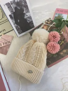 Berretto in maglia beige con grande pompon di pelliccia e dettaglio foglia di strass