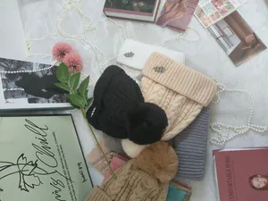 Selezione di berretti invernali in maglia con pompon di pelliccia e spille a foglia