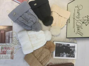 Collezione di berretti invernali in maglia a trecce con pompon in pelliccia in vari colori neutri