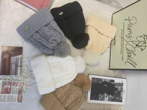 Dettaglio di berretti in maglia con pompon invernali in cinque colori neutri assortiti