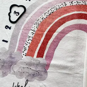 Détail en gros plan montrant la texture douce en flanelle et l'imprimé arc-en-ciel d'un tapis bébé