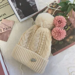 Berretto in maglia a trecce bianco crema con pompon in ecopelliccia e foglia di strass