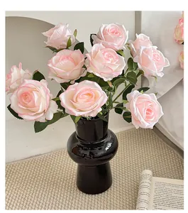 Macro detail of elegant artificial pink roses arranged in a modern black ceramic vase.