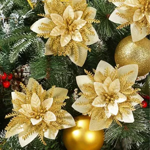 Primo piano di fiori di Natale artificiali dorati glitterati su sfondo di pino.