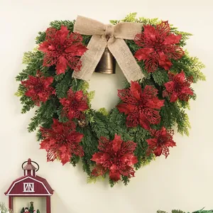 Festive green Christmas wreath with red glitter poinsettia flowers and a burlap bow