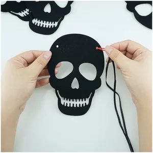 Close-up view showing the DIY assembly process of a black felt Halloween skull garland