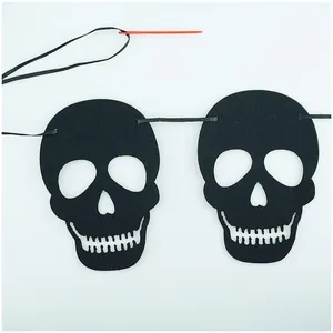 Detailed view of DIY Halloween black felt skull banner components with red plastic needle