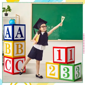 Enfant posant avec des boîtes à ballons ABC et 123 pour une décoration de rentrée scolaire.