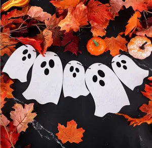 Halloween ghost banner decoration set amidst autumn leaves and mini pumpkins on black surface