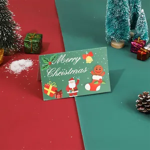 Gros plan d'une carte de Noël verte avec des motifs de Père Noël et d'homme en pain d'épices