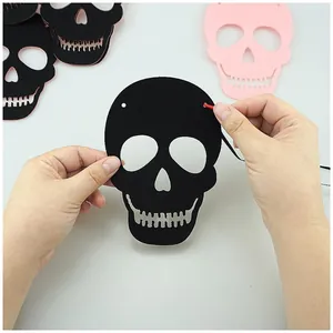 Close-up showing the DIY assembly process of a black felt skull garland for Halloween party