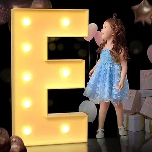 Grande lettera E luminosa per feste di compleanno con bambino e palloncini sullo sfondo