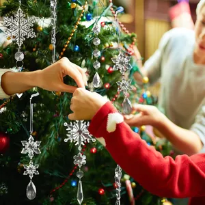Detailed view of acrylic Christmas snowflakes and icicles being hung on a festive tree.