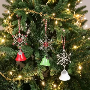 Set of three festive Christmas snowflake and bell ornaments hanging on a lighted tree