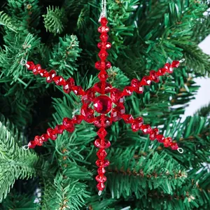 Dettaglio di un fiocco di neve in acrilico rosso appeso a un ramo di albero di Natale.