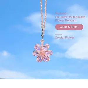 Detail view of a pink six-petal crystal flower suncatcher hanging against a blue sky