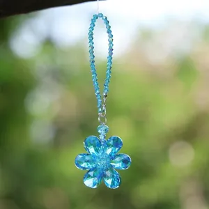 Detailed close-up view of a blue faceted crystal flower suncatcher in outdoor light