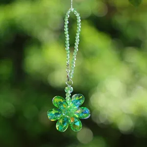Close-up of a green crystal flower suncatcher with rainbow prism effect for car decoration.