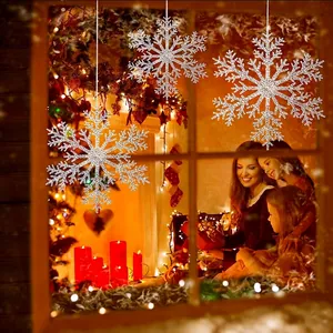 Adornos de copos de nieve plateados brillantes colgados en la ventana para Navidad.
