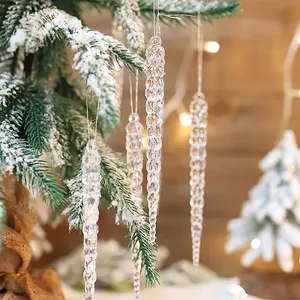 Detail view of clear acrylic icicle ornaments on a snowy Christmas tree