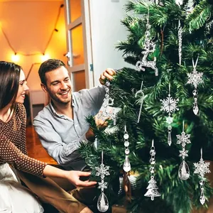 Famiglia decora l'albero di Natale con addobbi in acrilico trasparente a renna e fiocchi