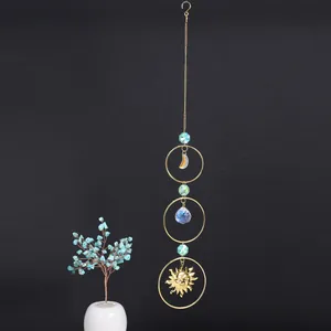 Detailed view of handcrafted crystal suncatcher with moon and sun face charms on a dark background