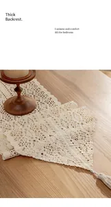 Close-up of white crochet lace table runner with tassel on wooden surface