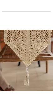 Detailed close-up showing the intricate openwork pattern and tassel of a cotton table runner