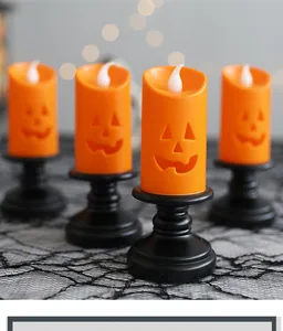 Detailed view of LED Halloween pumpkin candles on black stands with warm festive lighting
