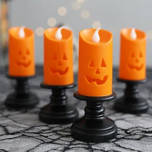 Set of 4 orange Halloween pumpkin LED candles on black stands for festive desktop decor