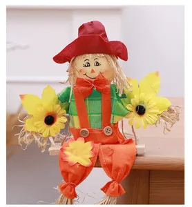 Detailed view of a cute smiling Halloween scarecrow doll sitting on a small wooden swing
