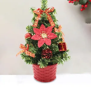 Petit sapin de Noël artificiel dans un panier rouge avec des nœuds et une fleur à paillettes.