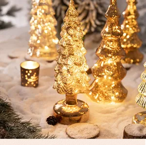 Albero di Natale in vetro mercurio luminoso su un tavolo festivo innevato