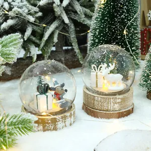 Due palle di neve natalizie a LED con figurine di renna e alce su basi rustiche di legno