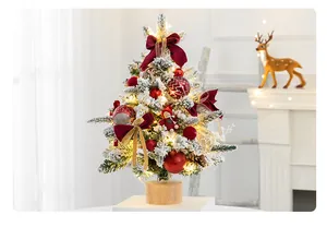 Gros plan d'un mini sapin de Noël enneigé avec des nœuds rouges et des lumières LED.