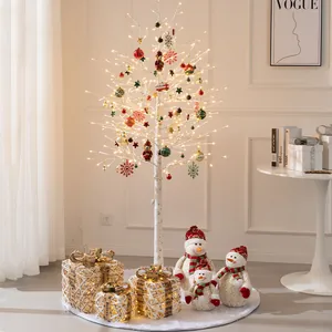 Elegante verlichte witte berken kerstboom met rode kerstballen en sneeuwpop decoratie.