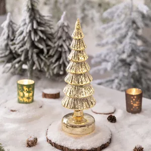 Elegant lighted gold mercury glass Christmas tree ornament on snowy winter holiday tabletop
