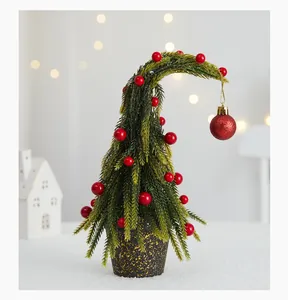 Gros plan d'un sapin de Noël artificiel courbé unique avec des baies rouges et boule