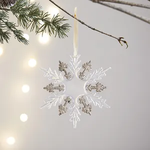 Eleganter Schneeflocken-Anhänger mit champagnerfarbenem Glitzer an einem Kiefernzweig