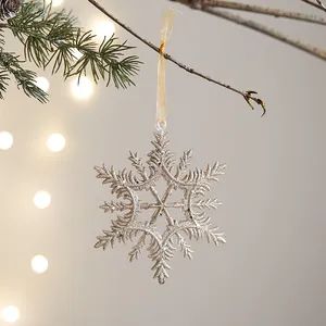Funkelnde champagner-goldene Schneeflocke Weihnachtsdeko an festlichem Tannenzweig.