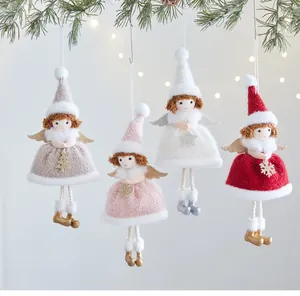 Detail of four plush Christmas angel girl doll ornaments hanging on a pine branch