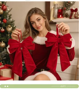 Close-up of red velvet long-tail bow ornaments held by a model in a Christmas setting
