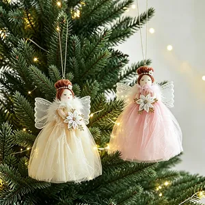 Pair of cute angel girl hanging ornaments with tulle dresses on a glowing Christmas tree