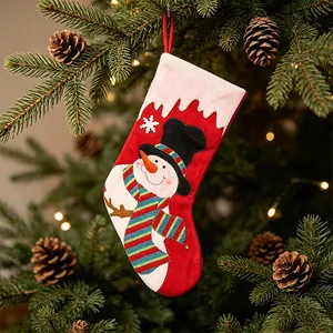 Dekorative rote Weihnachtssocke mit Schneemann-Applikation an einem Tannenbaum aufgehängt