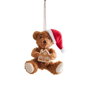 Cute brown plush Christmas bear hanging ornament with red Santa hat and gingerbread house