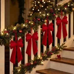 Red velvet long-tail Christmas bows hanging on a decorated staircase with festive lights