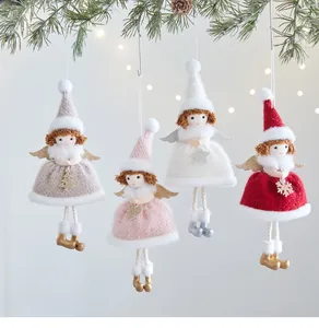 Vista dettagliata di quattro angeli di peluche colorati appesi a un ramo di pino natalizio.