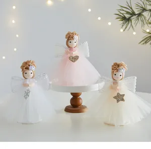 Three cute Christmas angel doll ornaments with tulle skirts and yarn hair on a stand.
