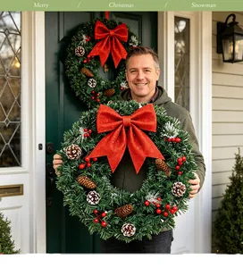 Homme souriant tenant une couronne de Noël classique avec un grand nœud rouge