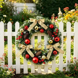 Couronne de Noël festive avec boules rouges et dorées sur une clôture de jardin blanche